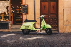 Green scooter in front of restaurant on cobblestone street