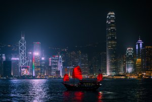 Red boat on the water in front of Hong Kong skyline at night