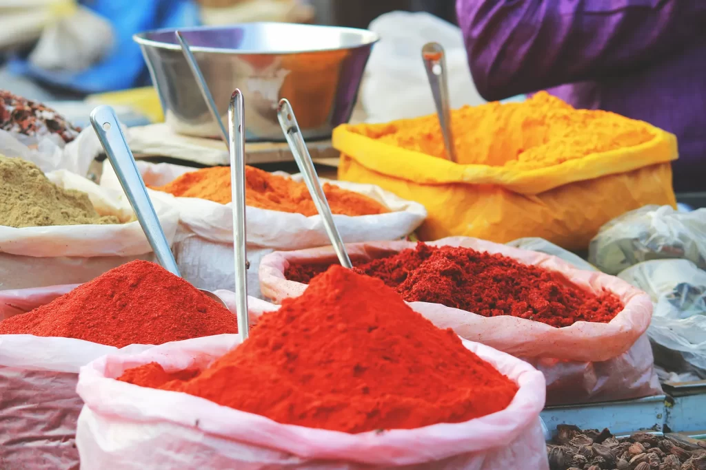 colorful spices in large bags with spoons sticking out