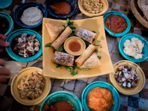 assortment of Moroccan dishes in small bowls with a bigger plate of food in the center