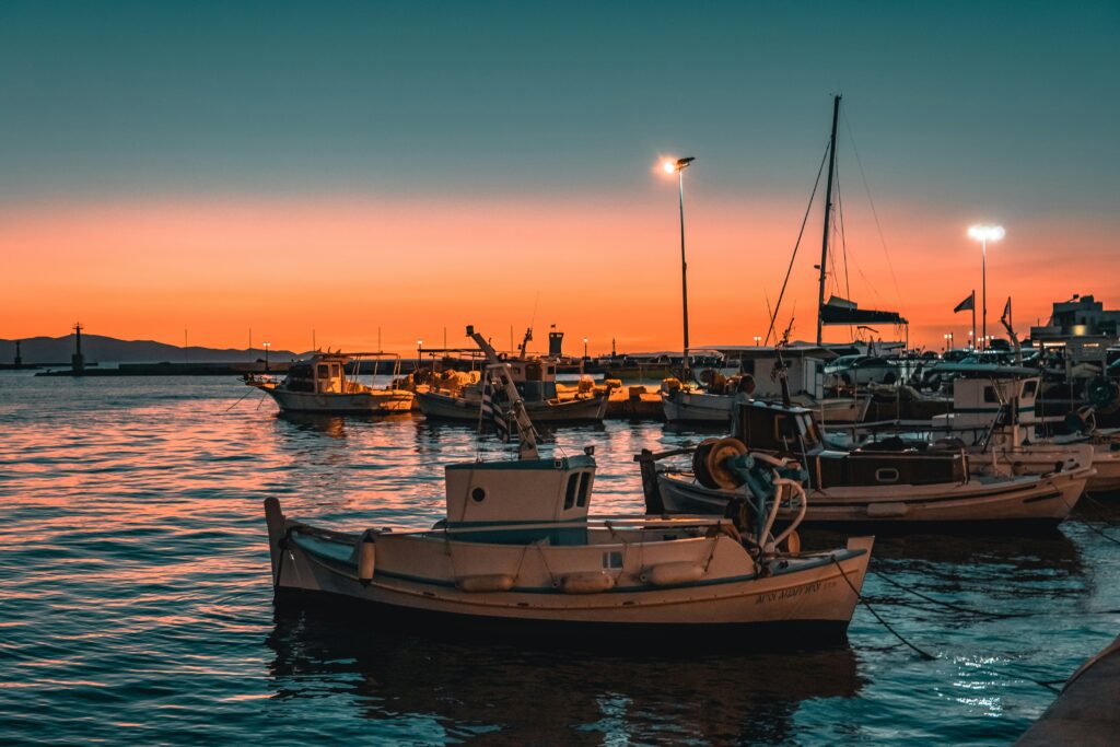 boats in a harbour at sunset with pink and orange colors in the sky