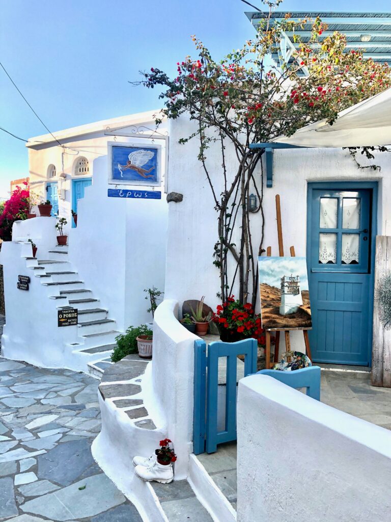 Typical Greek street with cobblestone road, white and blue houses and sparse vegetation