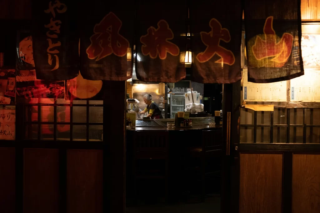 Woman cooking in a Japanese restaurant with decorative flags in the foreground