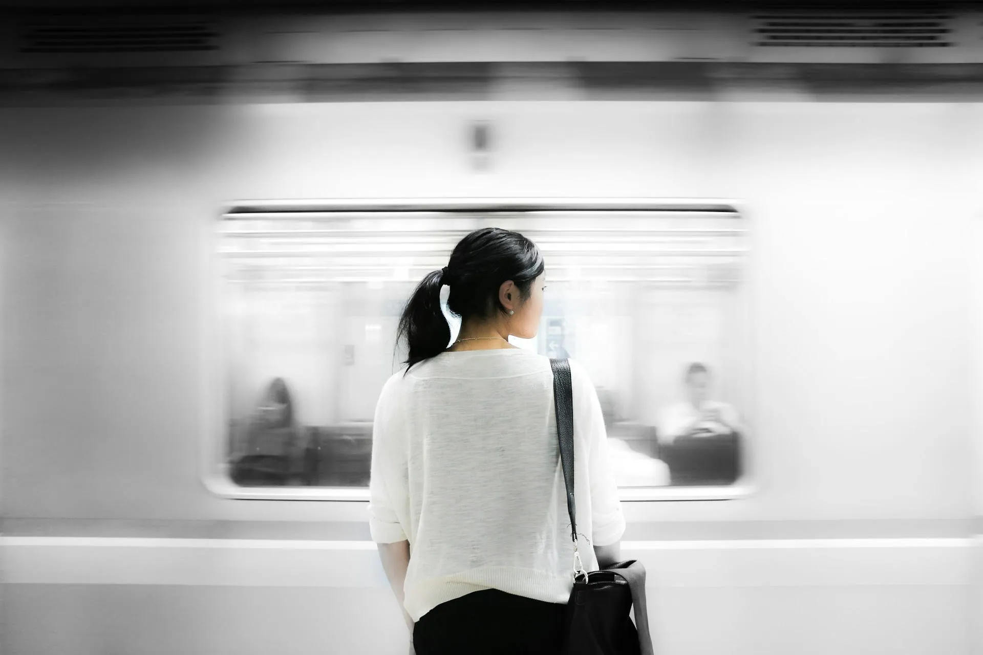 Woman waiting for a train with a blurry train passing in the background