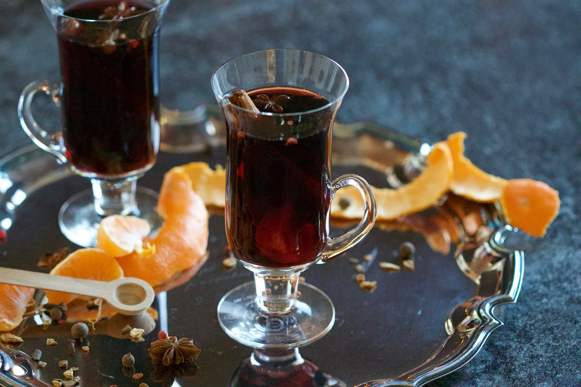 Danish glogg—mulled wine— in glasses on a silver tray, with orange peel and spices on the tray around the glasses