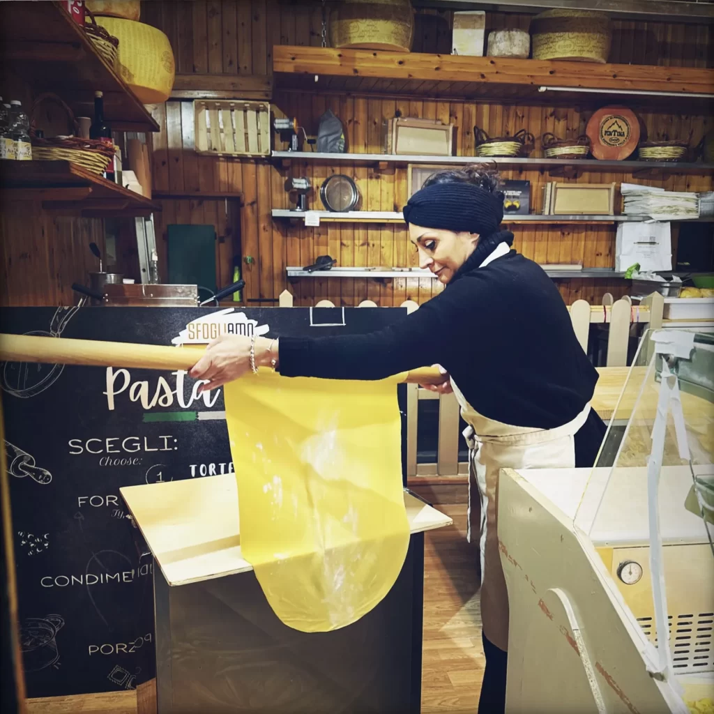 Expert pasta maker holding up sfoglia in a pasta making class in Emilia Romagna